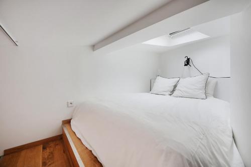 - une chambre avec un grand lit blanc et des oreillers blancs dans l'établissement Appartement charmant avec vue - Montmartre, à Paris