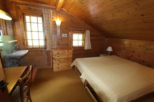 ein Schlafzimmer mit einem Bett und einem Waschbecken in einer Hütte in der Unterkunft Arnica 2 in Chateau-d'Oex