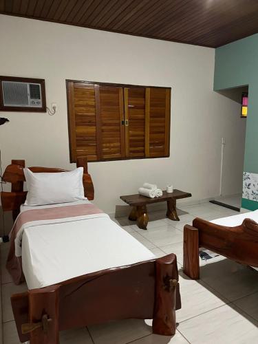 a bedroom with two beds and a table at Pousada Aconchego in Pirenópolis