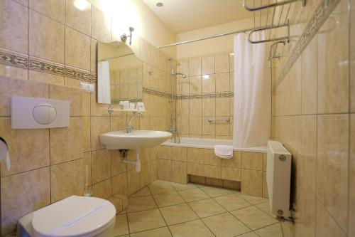 a bathroom with a toilet and a sink and a tub at Hotel Garden in Bolesławiec