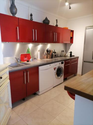 - une cuisine avec des placards rouges et un lave-linge dans l'établissement Plein soleil et plage, à Fréjus