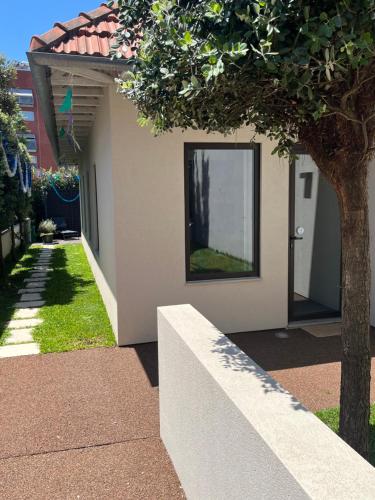 a white house with a tree and a wall at JM Alojamento local no Porto in Porto