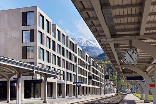 a train station with a clock hanging from a building at Essential by Dorint Interlaken - New Opening in Interlaken