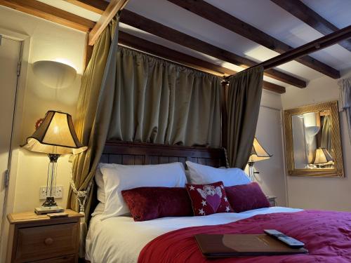 a bedroom with a canopy bed with a book on it at Guiting Guest House in Guiting Power