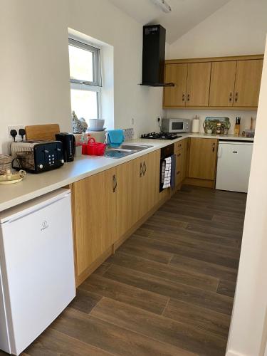 a kitchen with wooden cabinets and a wooden floor at Memory Lane Self Catering Cottage in Muckros