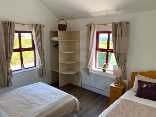 a bedroom with two beds and two windows at Memory Lane Self Catering Cottage in Muckros