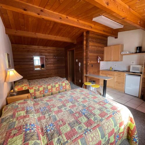 a bedroom with two beds and a kitchen in a cabin at Raccoon Lodge Motel in Sylvan Lake