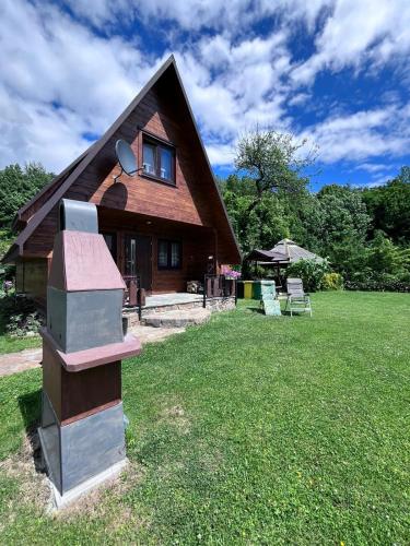 a house with a thatched roof on a lawn at Domki pod Skałką in Baligród