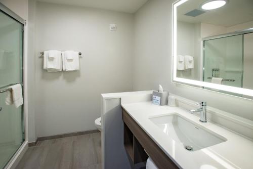 a white bathroom with a sink and a mirror at Holiday Inn Express & Suites Pensacola Airport North – I-10 by IHG in Pensacola