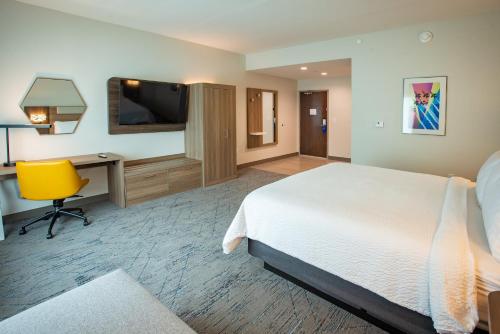 a hotel room with a bed and a desk and a television at Holiday Inn Express & Suites Pensacola Airport North – I-10 by IHG in Pensacola