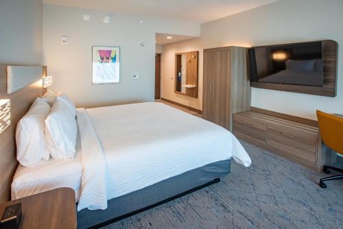 a hotel room with a bed and a flat screen tv at Holiday Inn Express & Suites Pensacola Airport North – I-10 by IHG in Pensacola