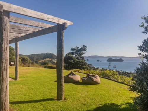 a wooden pergola with a view of the water at The Grandstand - Hahei Holiday Home in Hahei