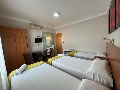Habitación de hotel con 3 camas y mesa en Pensión Laforja, en Barcelona