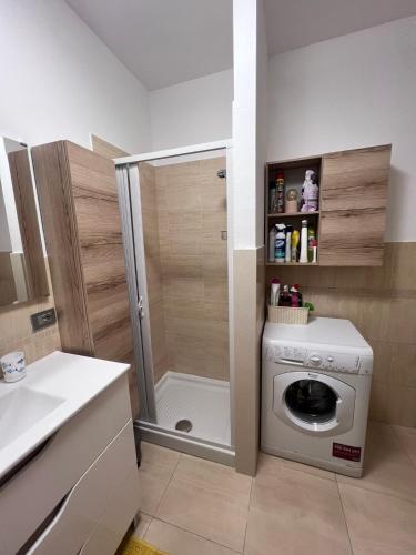 a small bathroom with a washing machine and a shower at Casa Antia, nuovo bilocale con giardino in Residence con piscina in Numana