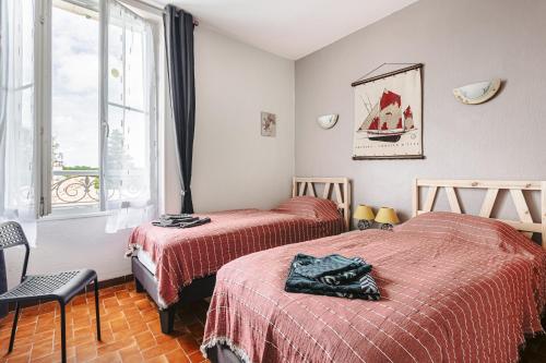 two beds in a room with a window at Gite les Cigognes in Marennes