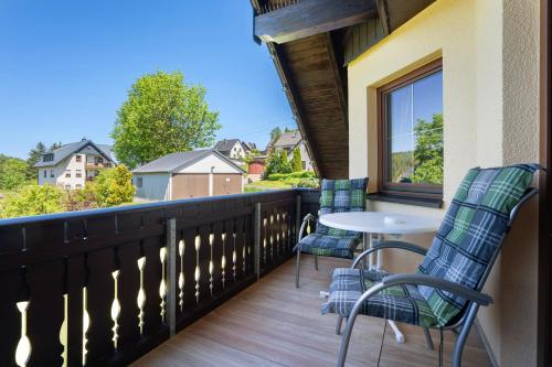 a balcony with two chairs and a table and a window at Pension Bergblick in Marienberg