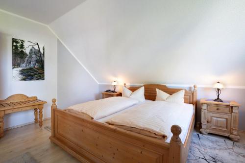 a bedroom with a large wooden bed with white sheets at Pension Bergblick in Marienberg