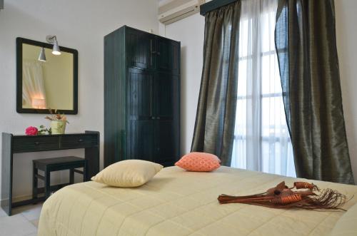 a bedroom with a bed with a dresser and a mirror at Dilino Hotel Studios in Agios Prokopios