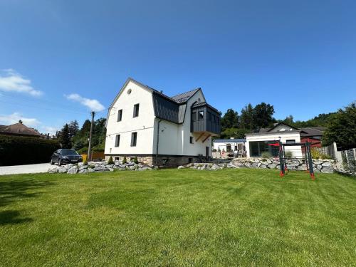 a white house with a playground in a yard at Vila Kosmonautka - Velké Losiny in Velké Losiny