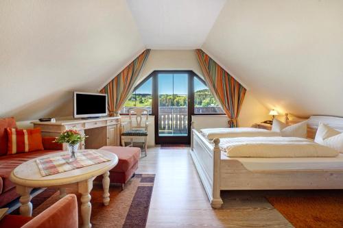 a attic room with a bed and a table and a tv at Pension Bergblick in Marienberg
