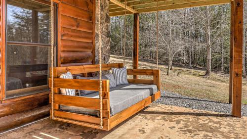 a bed on the porch of a log cabin at Tranquility Ranch in Mineral Bluff