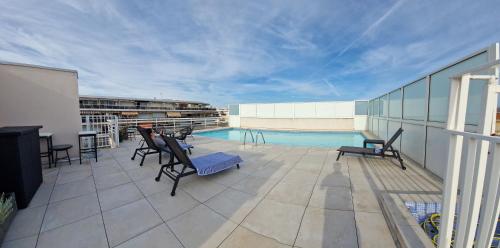 - un balcon avec des chaises et une piscine dans un bâtiment dans l'établissement Juan 4 prs, clim, 300m plage, piscine, parking, à Antibes