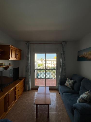 a living room with a blue couch and a table at Apartamento La Atalaya C-162 in Conil de la Frontera