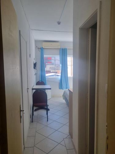 a hallway with a desk and a window with blue curtains at Hotel Kolman in Capão da Canoa
