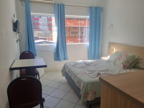 a bedroom with a bed and a desk and a window at Hotel Kolman in Capão da Canoa