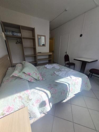 a bedroom with a large bed with pink sheets at Hotel Kolman in Capão da Canoa