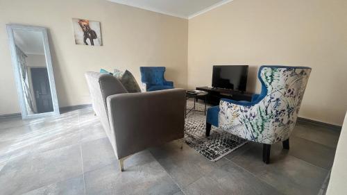 a living room with two chairs and a television at Stylish Self Catering Unit in Maseru CBD in Maseru