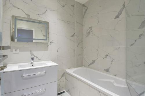 La salle de bains blanche est pourvue d'une baignoire, d'un lavabo et d'un miroir. dans l'établissement 4P haut de gamme Nice Ouest Promenade des anglais, à Nice