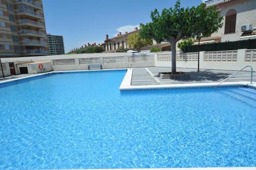 una gran piscina azul con un árbol. en Apartamentos Estoril I - II Orangecosta en Benicàssim
