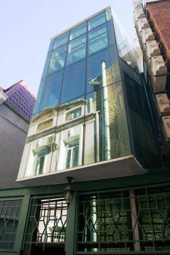 a tall glass building with a reflection of a building at Tbiliseli Inn in Tbilisi City