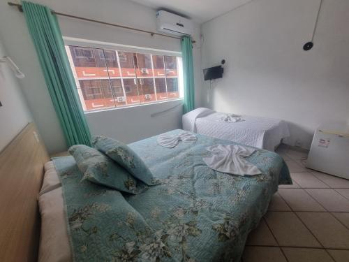 a small bedroom with a bed and a window at Hotel Kolman in Capão da Canoa