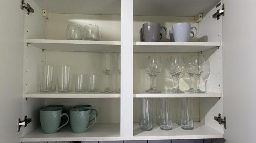 コルチェスターにあるDK Houseのワイングラスとカップが入った棚
