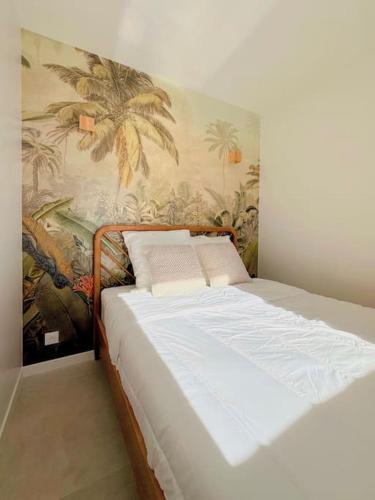 Ce lit se trouve dans un dortoir orné d'une fresque murale de palmiers. dans l'établissement Vue mer - Refait à neuf - Clim - Parking - 4 personnes, à Théoule-sur-Mer