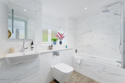 een witte badkamer met een bad, een toilet en een wastafel bij Corner Cottage in Penzance