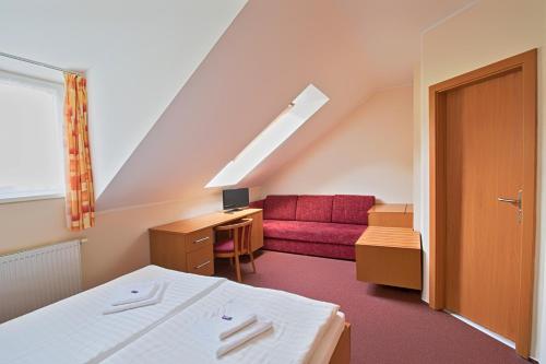 Habitación con cama y sofá rojo en Hotel České Žleby en Stožec