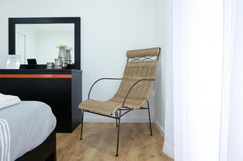a wicker chair sitting next to a desk in a bedroom at Avenida House 1 in Ponta Delgada