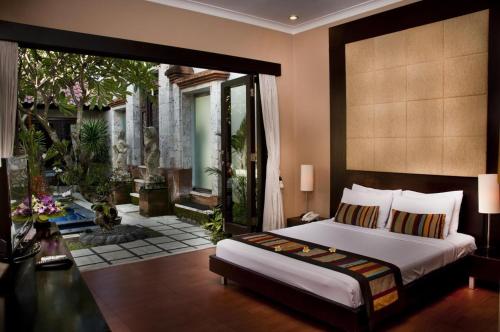 a bedroom with a large bed and a patio at Sindhu Mertha Suite in Sanur