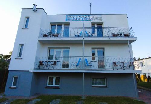 ein Gebäude mit Tischen und Stühlen auf dem Balkon in der Unterkunft Dom Gościnny Maja - Pokoje in Mrzeżyno