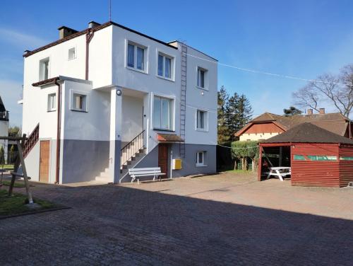 ein weißes Haus mit einer Bank davor in der Unterkunft Dom Gościnny Maja - Pokoje in Mrzeżyno