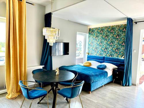 ダルウフコにあるSunset Apartments Kropla Baltykuのベッドルーム(青いベッド1台、テーブル付)