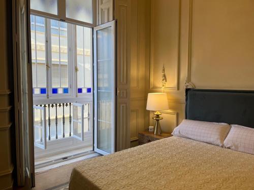 a bedroom with a bed and a large window at Apartamentos Loles De Cisneros Catedral in Málaga