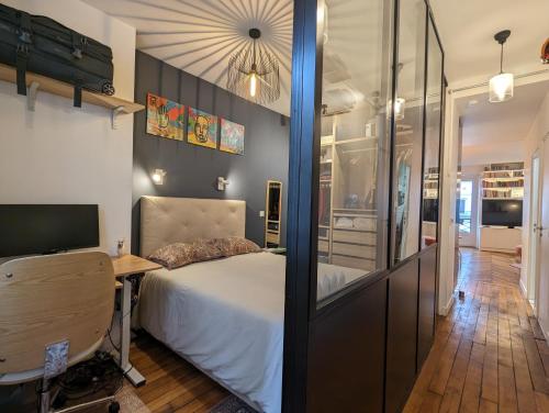 une chambre avec un lit, un bureau et une télévision dans l'établissement Appartement élégant - Fbg Saint Denis, à Paris