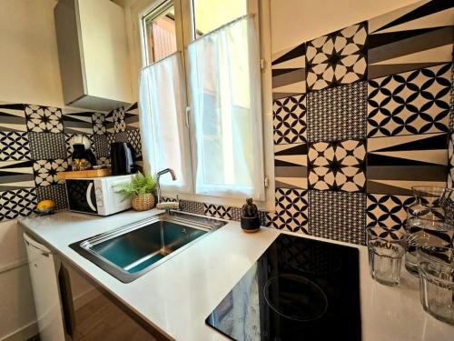 une cuisine avec un évier et un micro-ondes dans l'établissement Le Pastel - centre ville - clim, à Nîmes
