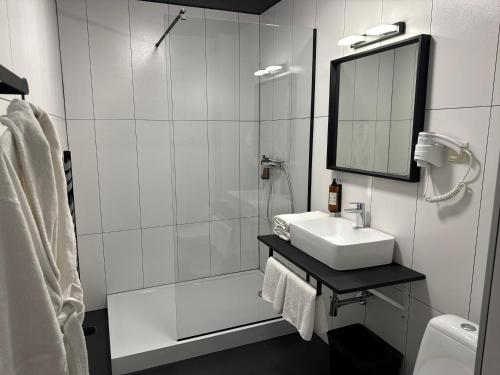 a bathroom with a sink and a shower with a mirror at Amber Blue Wellness & SPA in Karwia