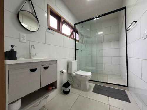 een badkamer met een toilet en een glazen douche bij Suíte na casa amarela in Pomerode