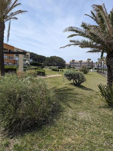 un parc avec des palmiers et un bâtiment dans l'établissement T2 à 200m de la mer et commerces, à Six-Fours-les-Plages